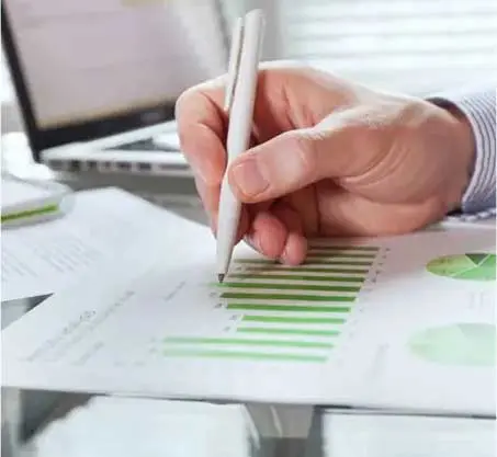 A person writing on paper with green and white graphs.